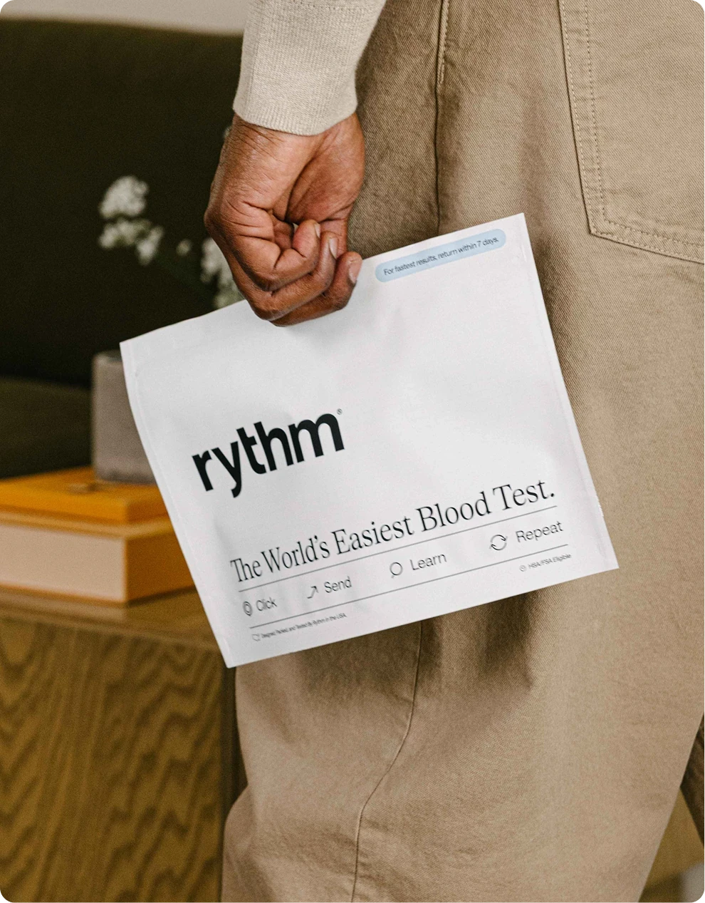 Woman sitting and smiling with a Rythm device on her arm, with text “The World’s Easiest Blood Test.”