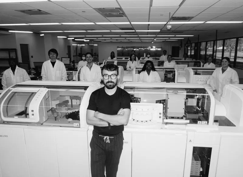 Robby Wade, CEO of Rythm Health, standing with the lab team behind automated diagnostic machines in a clinical testing facility.