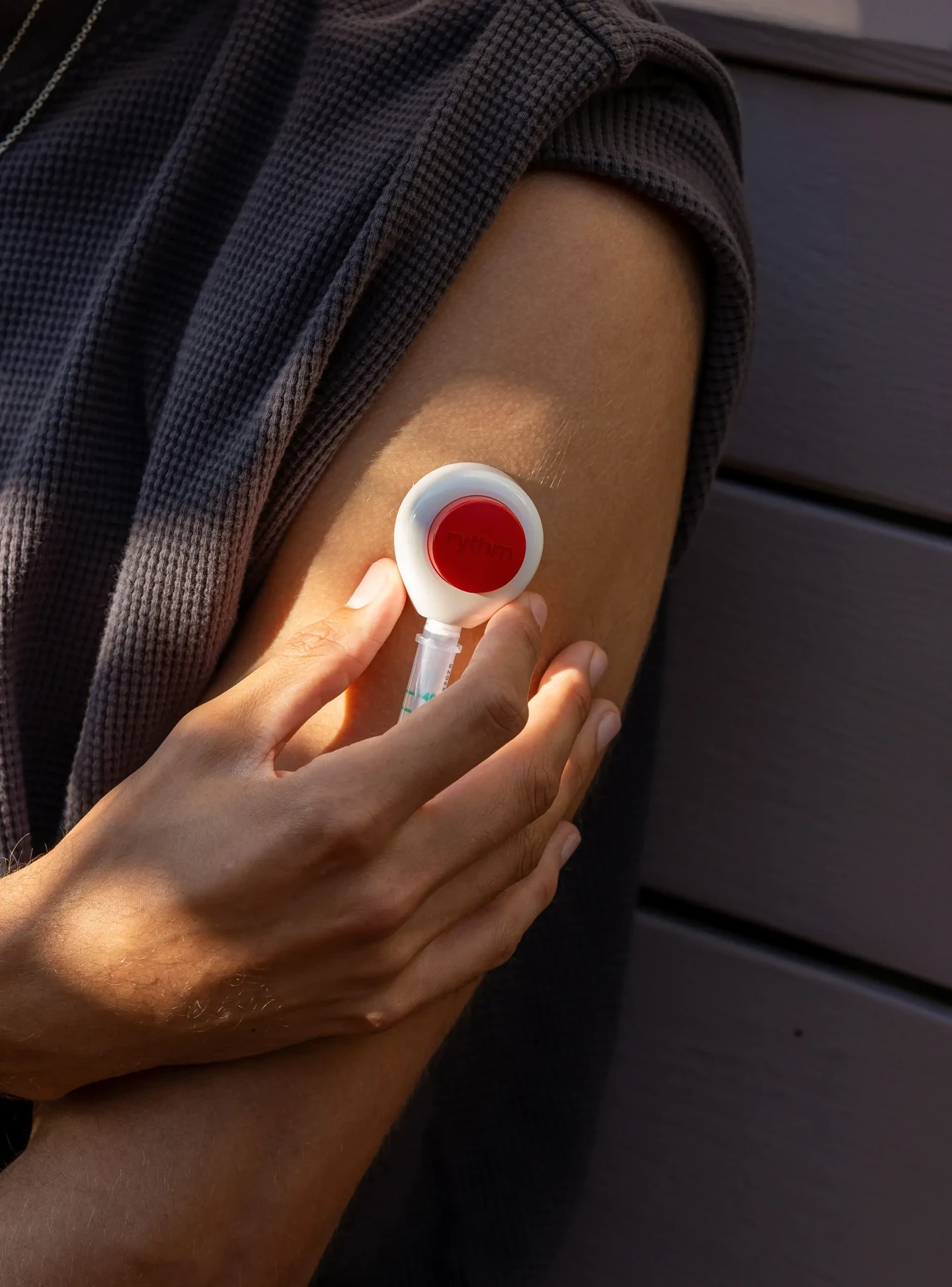 Close-up of a person placing a Rythm device on their upper arm.