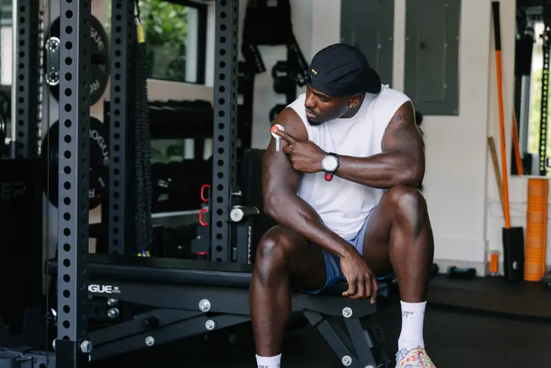 Man seated in a gym adjusting a Rythm Health sensor on his upper arm during a workout.