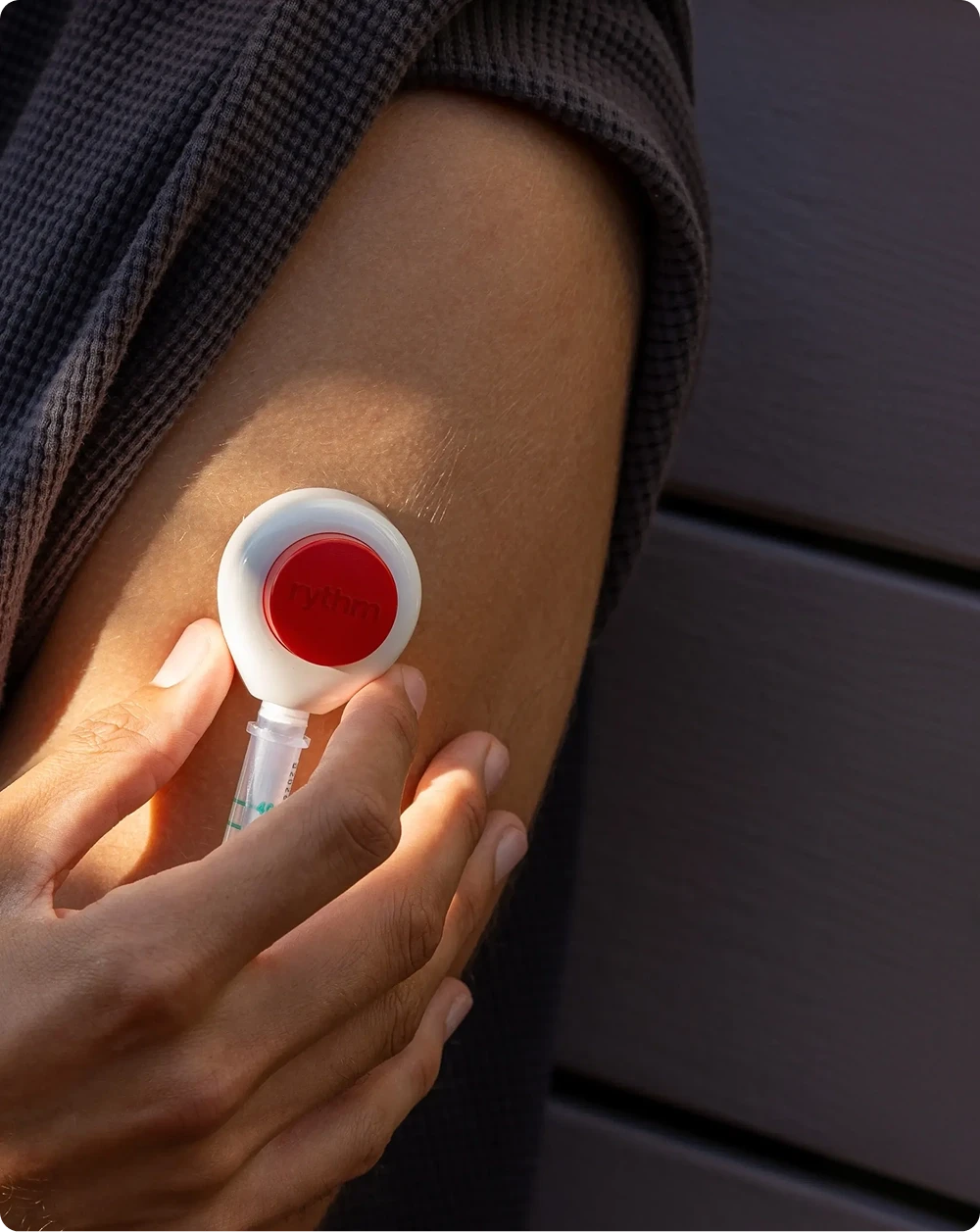 Close-up of a person placing a Rythm device on their upper arm.