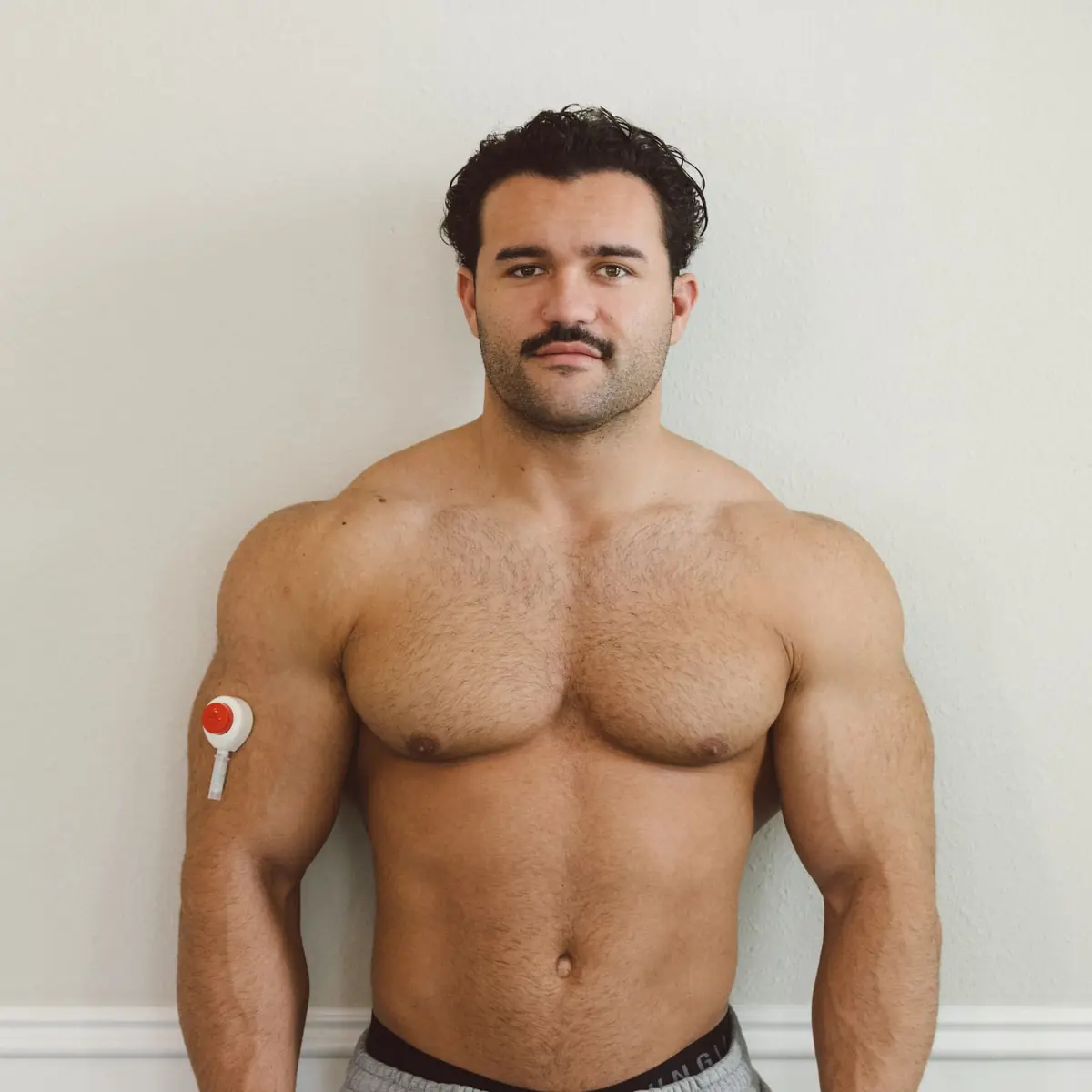 Jam standing shirtless wearing a Rythm Health sensor on his upper arm.