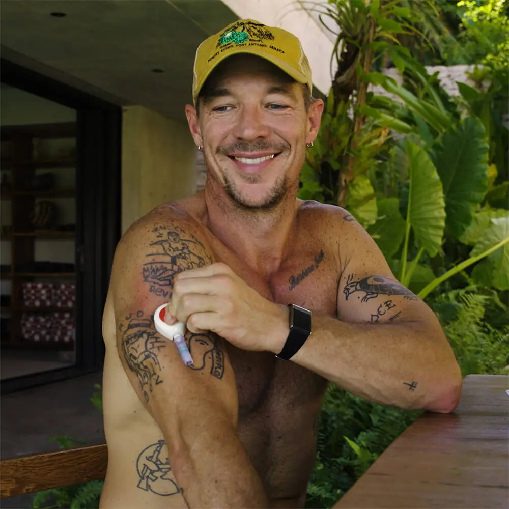 Diplo outdoors applying a Rythm Health sensor to his upper arm.