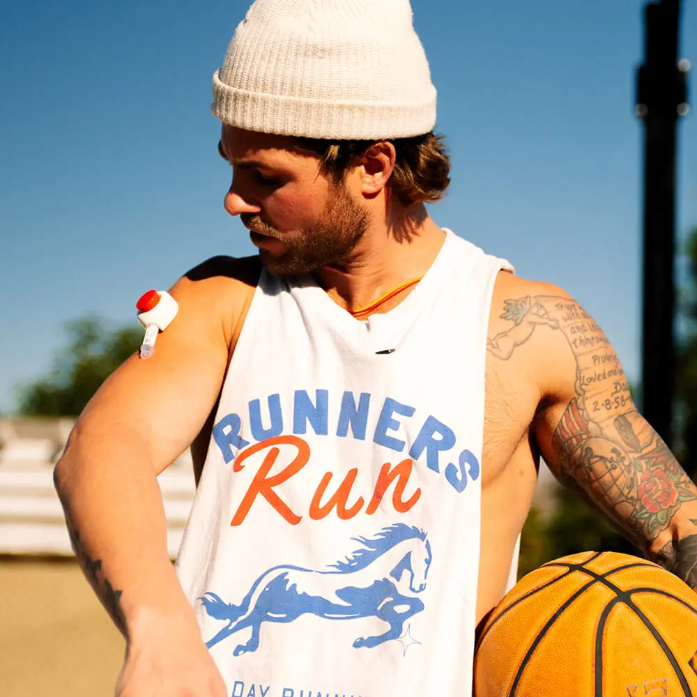 Devon outdoors holding a basketball while wearing a Rythm Health sensor on his upper arm.