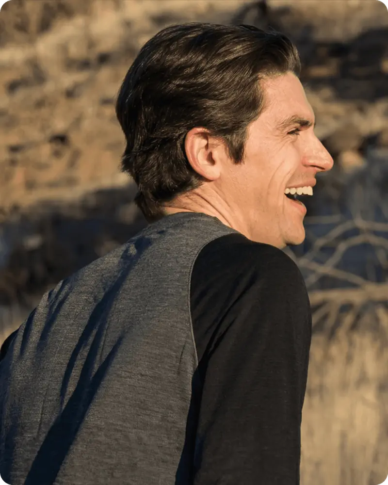 Man smiling outdoors in natural light, representing a healthy and active lifestyle.
