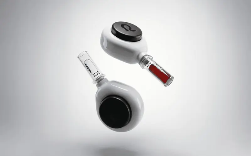 Two Rythm Health devices floating against a clean background, one showing a filled blood sample vial.