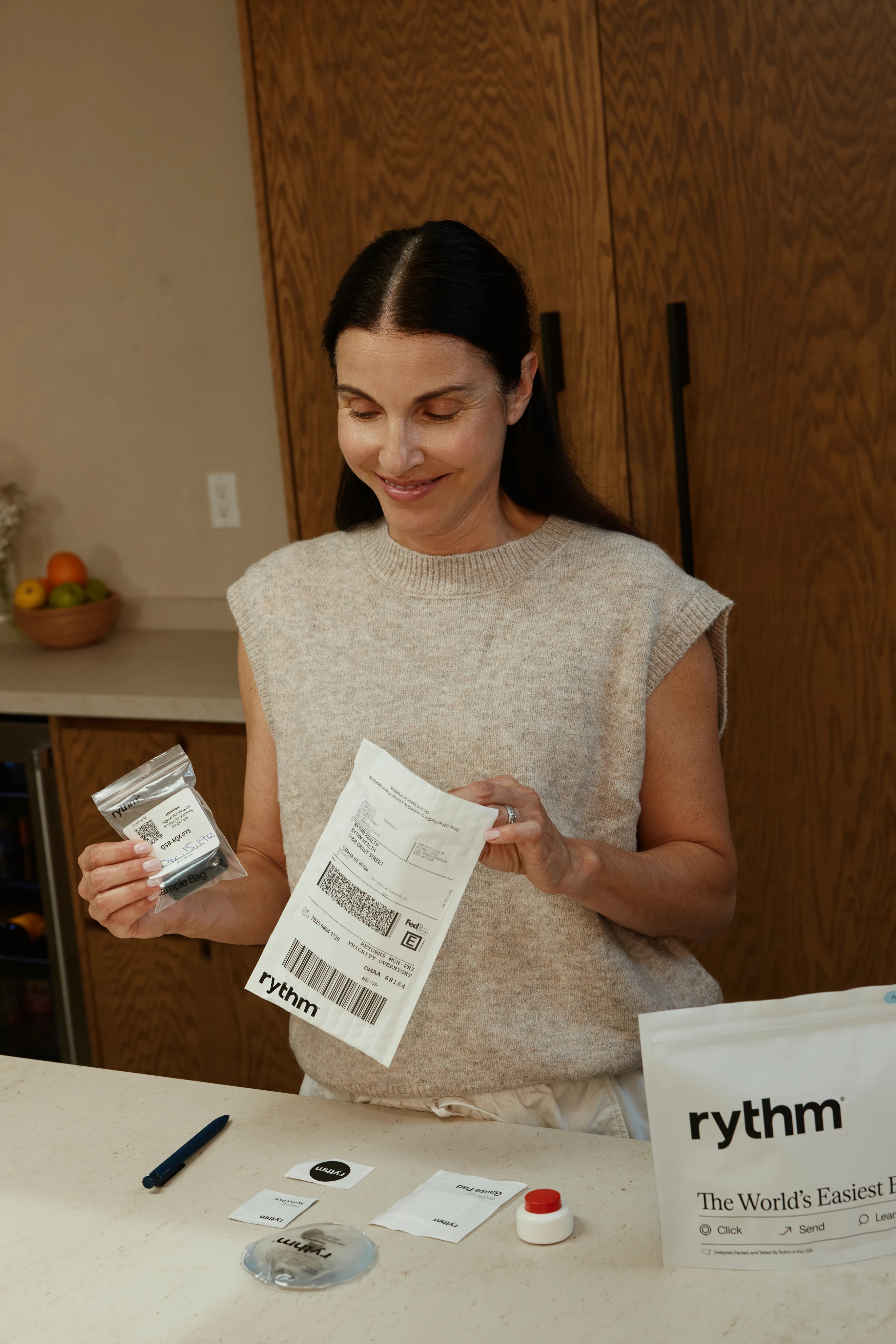 Two hands exchanging a Rythm test kit with packaging visible.