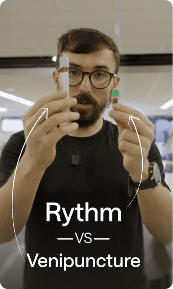 Robby Wade, CEO of Rythm Health, holding two blood collection devices side by side for comparison, labeled “Rythm vs Venipuncture.”