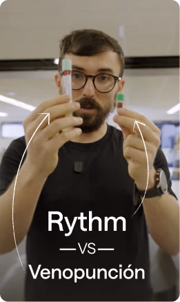 Robby Wade, CEO de Rythm Health, sosteniendo dos dispositivos de recolección de sangre lado a lado para compararlos, etiquetados como "Rythm vs. Venopunción".
